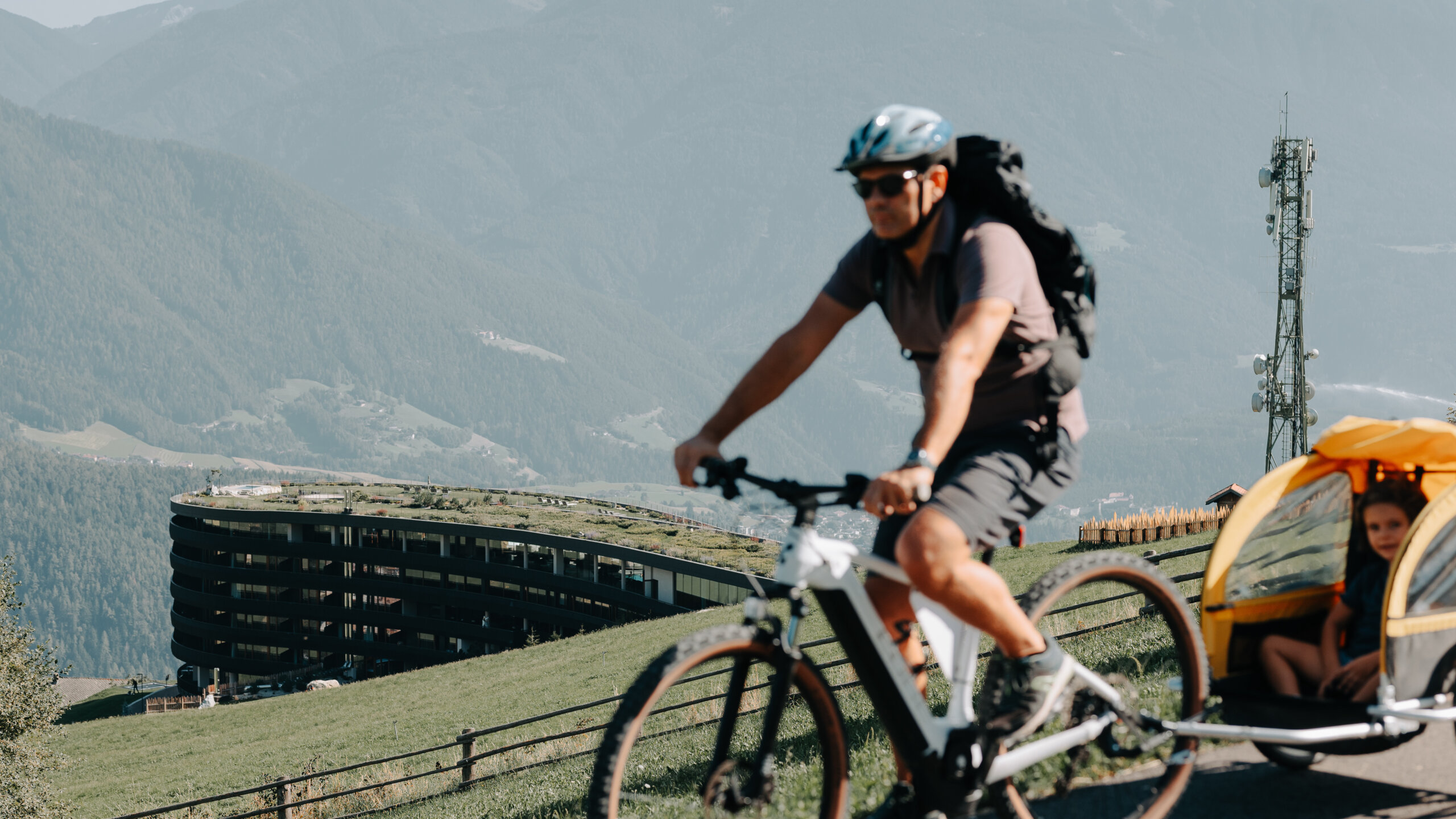 Radfahrer mit Kind auf dem Radweg, im Hintergrund das Hotel Familiamus